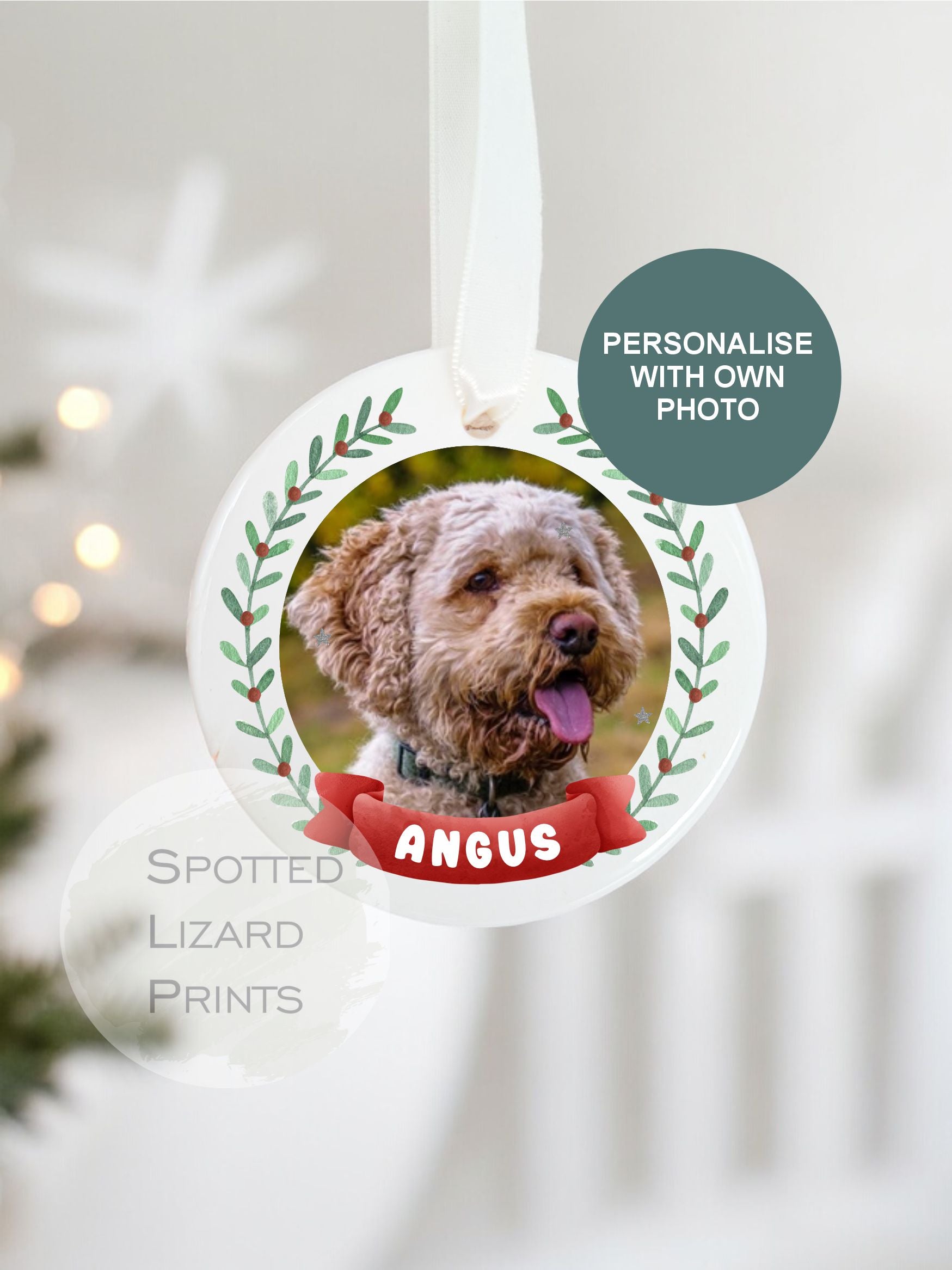 Personalised ceramic Christmas bauble featuring a photo of a dog, framed by a festive green wreath design and a red banner with the dogs name, hanging on a white ribbon